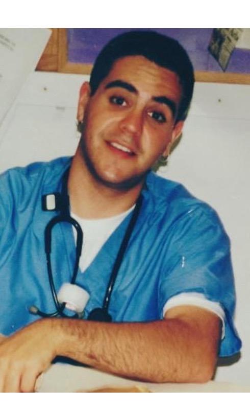 Eric Barna in blue scrubs as a patient care associate in 1999, before medical school