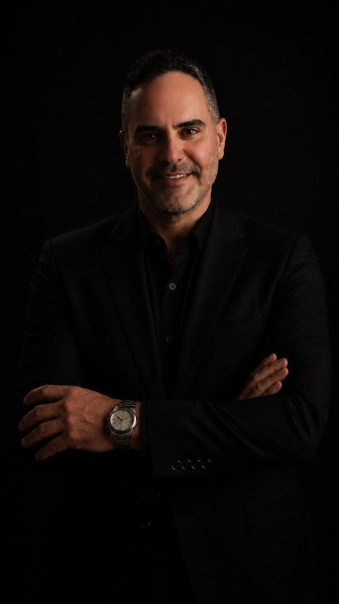 Eric Barna, MD MPH, in a black suit against a dark background.